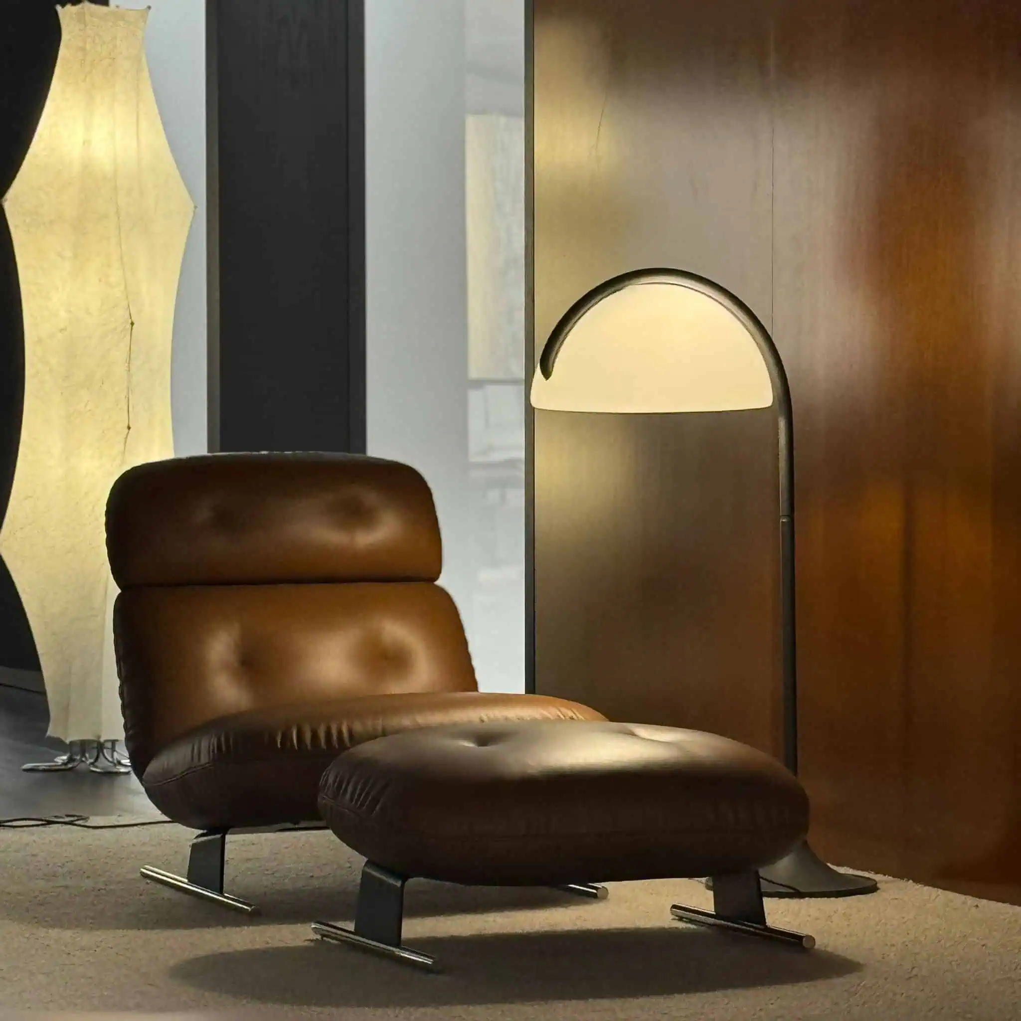 luxurious brown leather lounge chair with matching ottoman and a contemporary floor lamp, set against a wood-paneled wall in a sophisticated interior