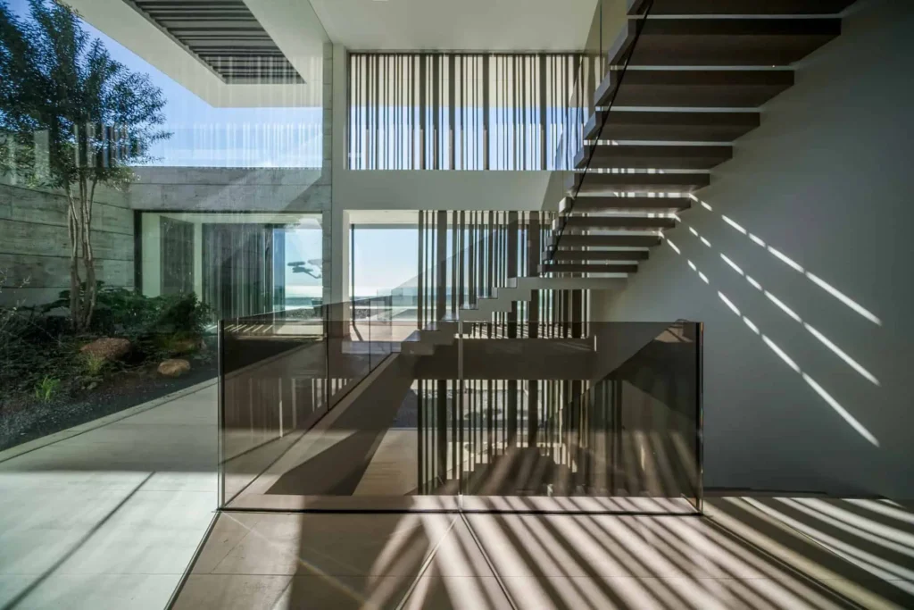 modern living room with natural light streaming across a textured travertine wall, illustrating how material and light create emotion and atmosphere in ARK Architects’ design philosophy