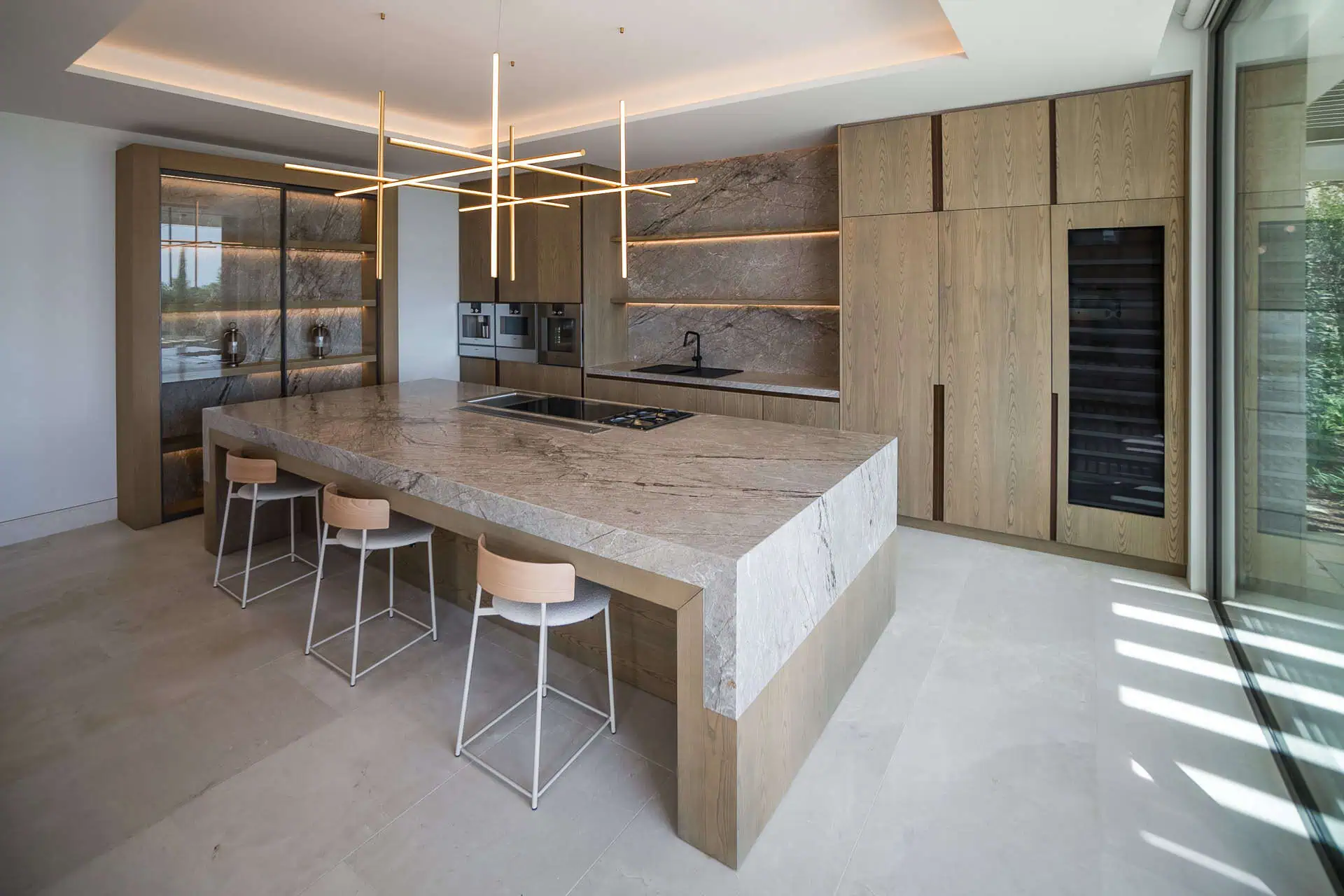 villa kaizen in la zagaleta modern ARK Architects kitchen with a large island, showcasing personalized design and multisensory materials that connect the kitchen and living area.