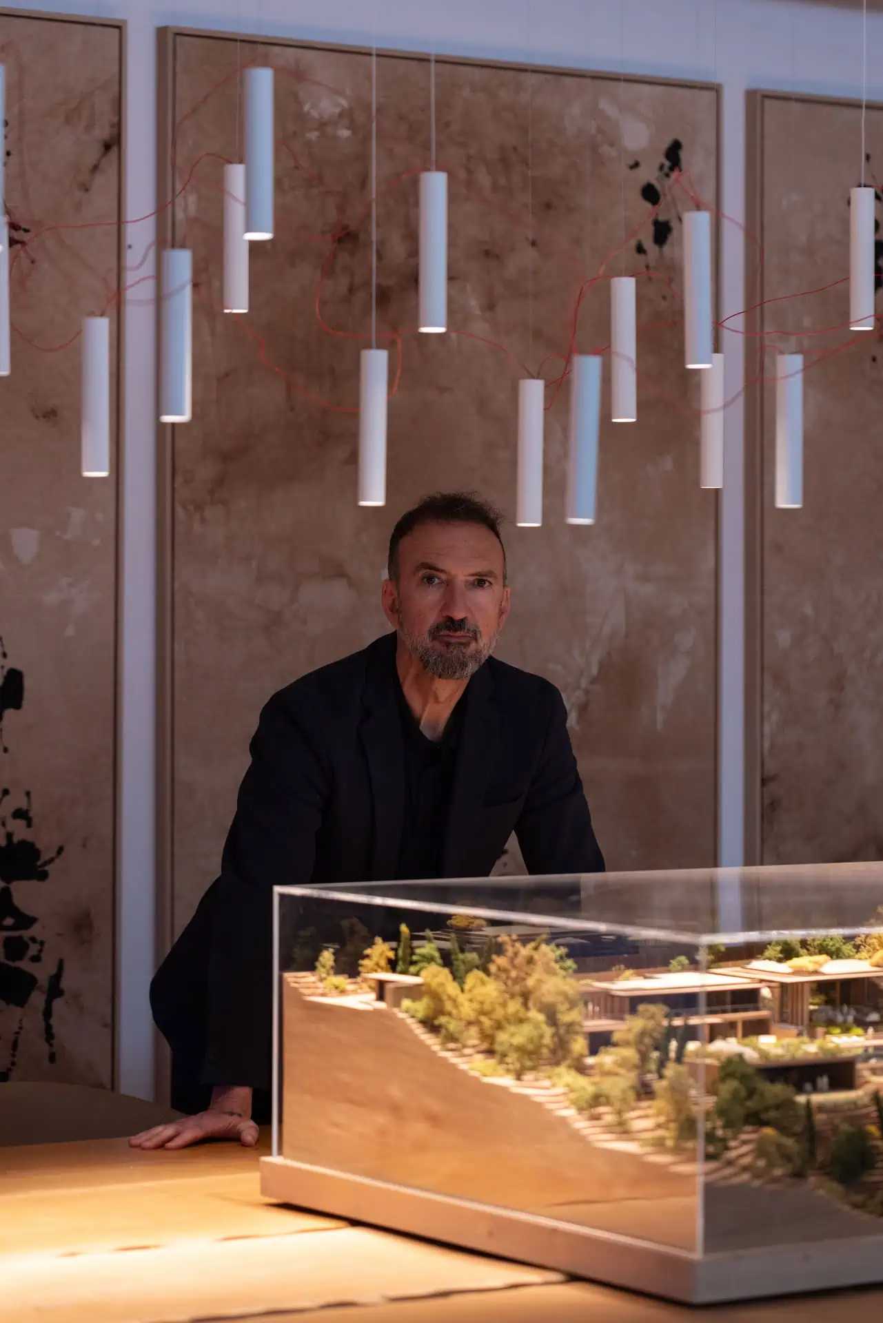 Manuel Ruiz Moriche presenting scale model of modern villa TAI at design studio in Sotogrande, featuring contemporary pendant lights and creative workspace by ARK Architects.