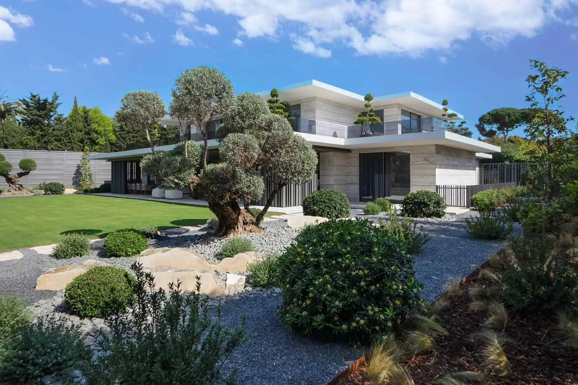 Contemporary Mediterranean villa with manicured garden, olive trees, and architectural landscaping by ARK Architects in Sotogrande