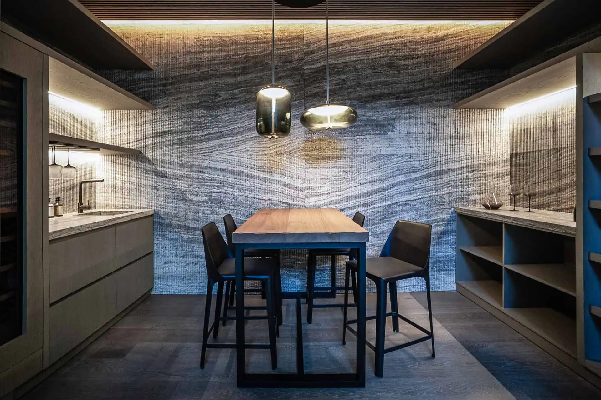 kitchen space at Villa Geneve la zagaleta with veined stone wall wood table and pendant lights​ by ark architects
